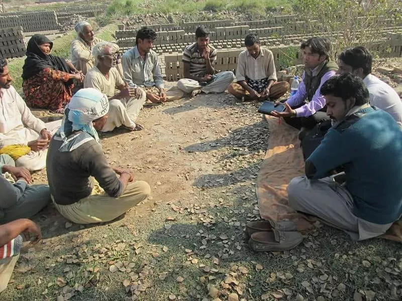 Church missionaries praying with brick kiln workers during humanitarian outreach